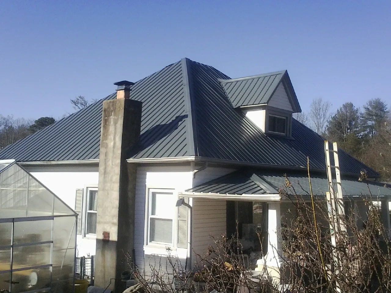 Dark blue standing seam metal roof on a white farmhouse with dormer — Slate & Tile Roof Repair by Roofing Brothers in Woodbury