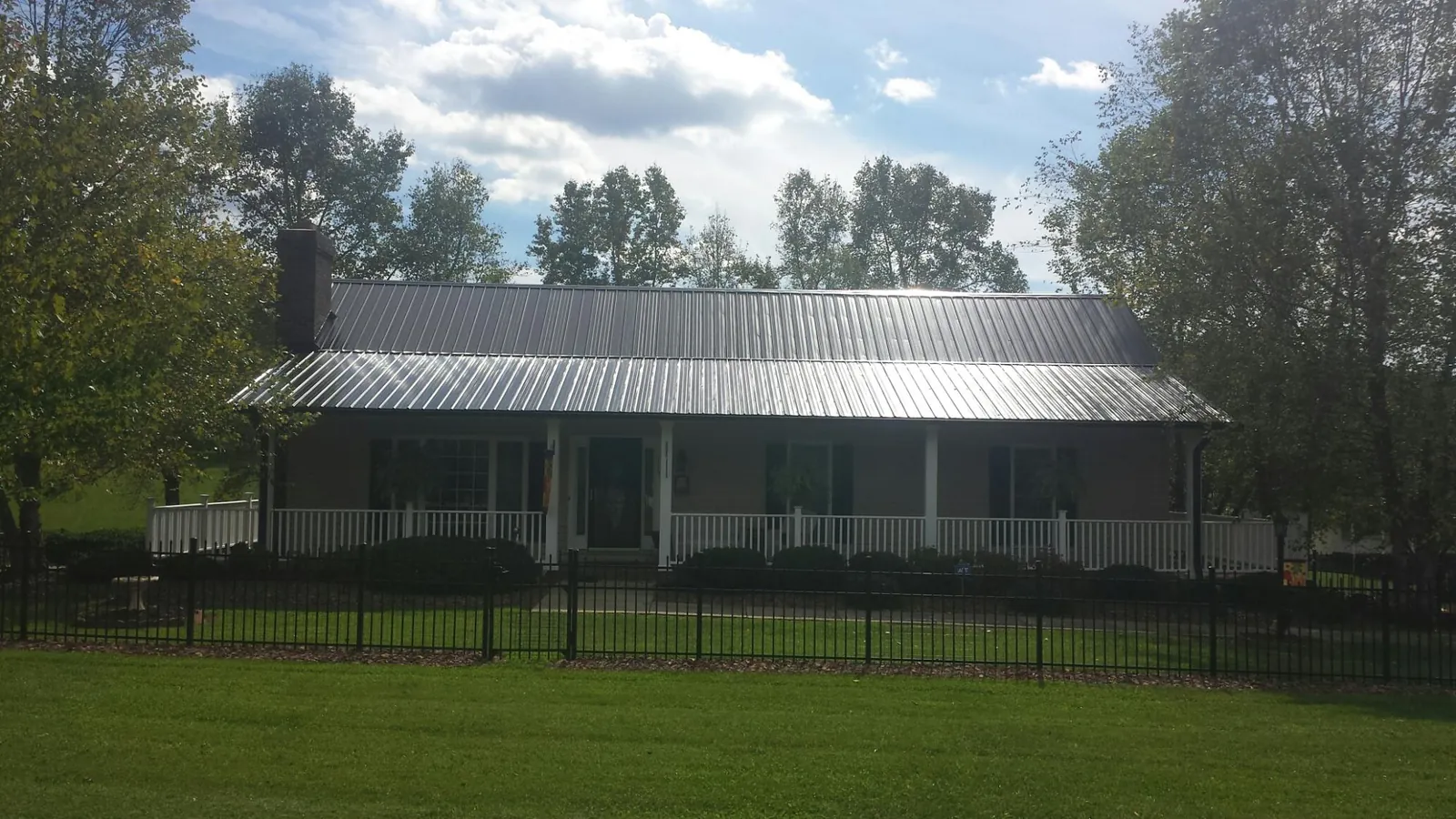 Gray metal roof on a brick ranch with a full width front porch — Gutter Guard Installation work by our crew in Woodbury